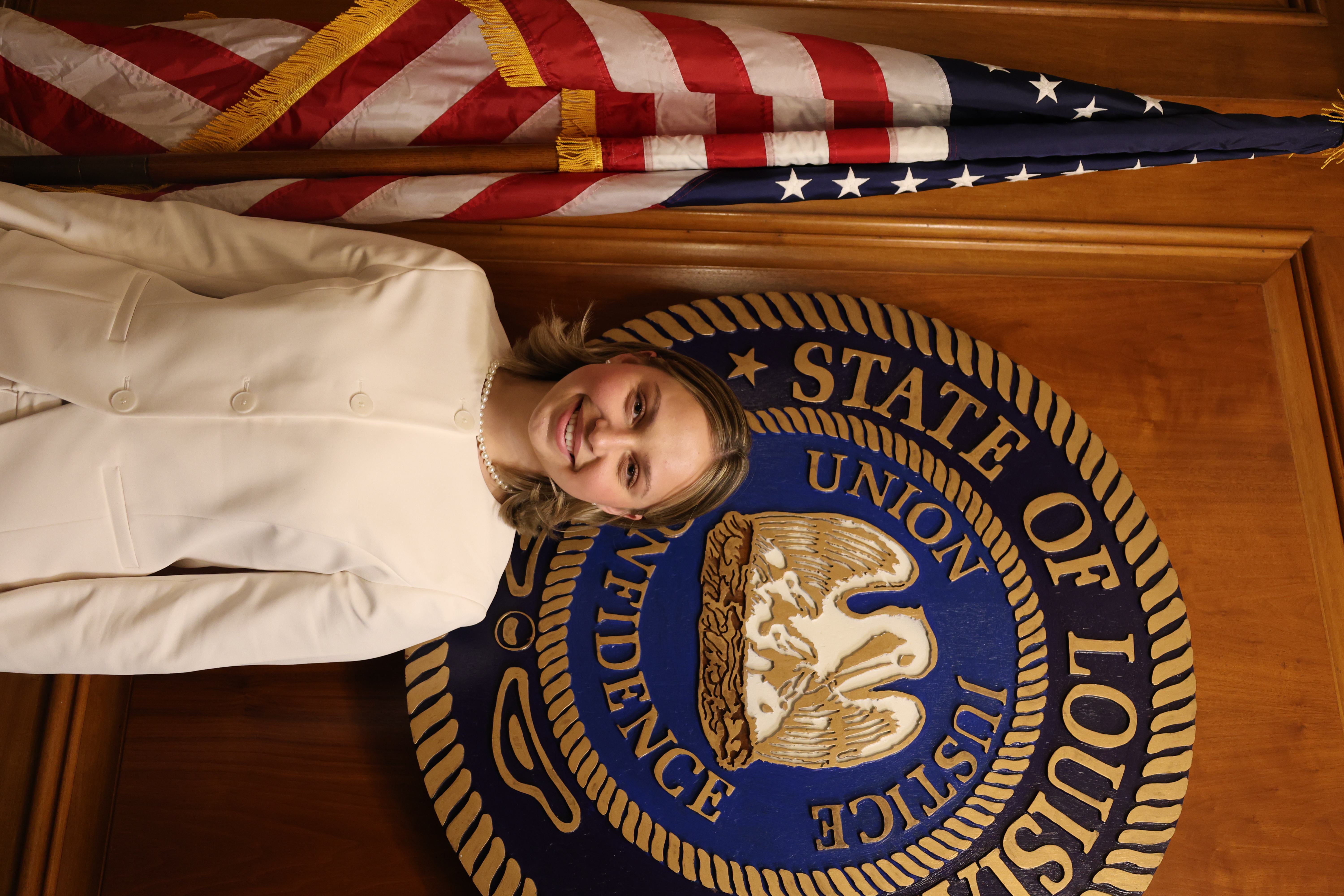 Headshot of girl in front of the Louisiana State symbol and American Flag