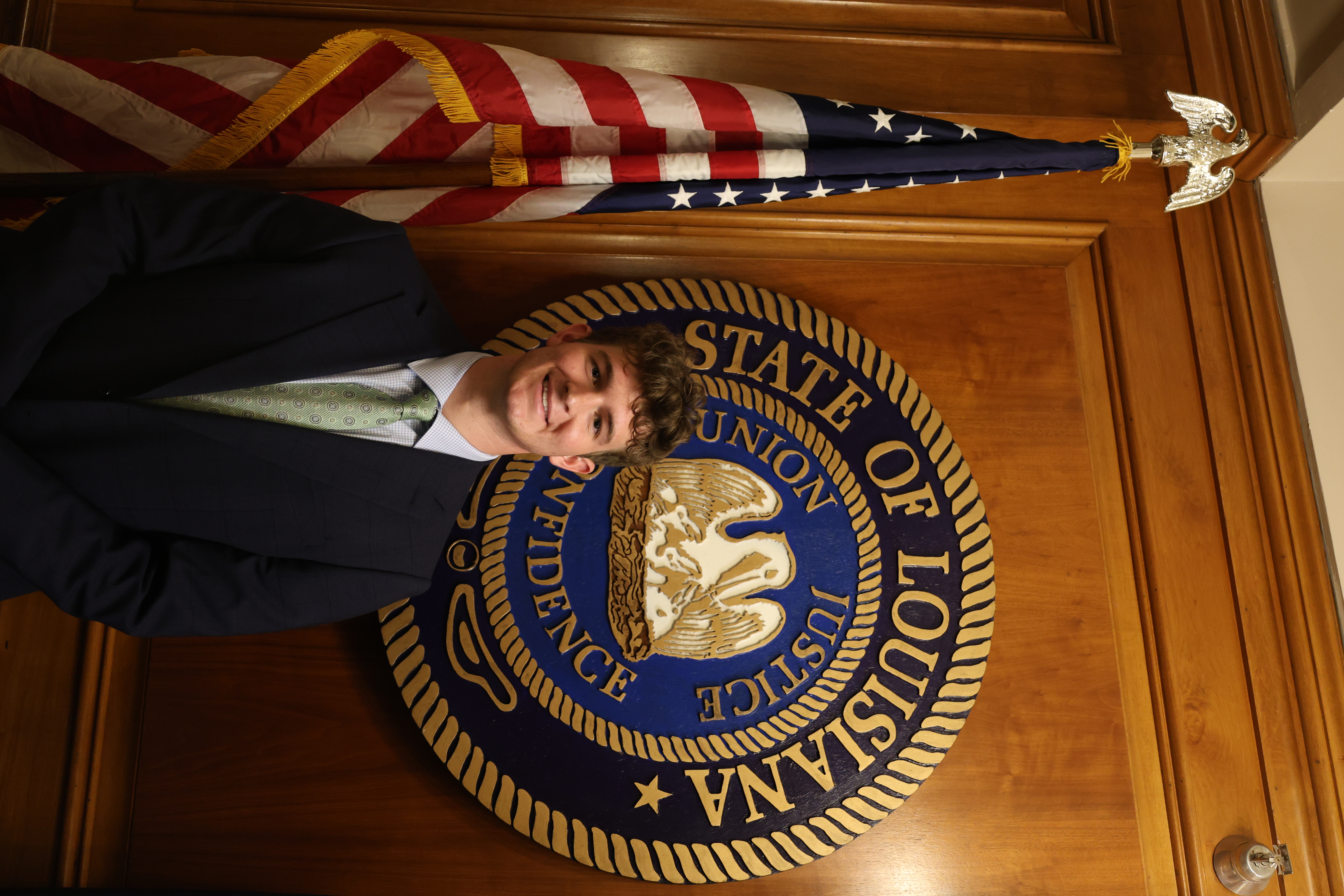Headshot of boy in front of the Louisiana State symbol and American Flag